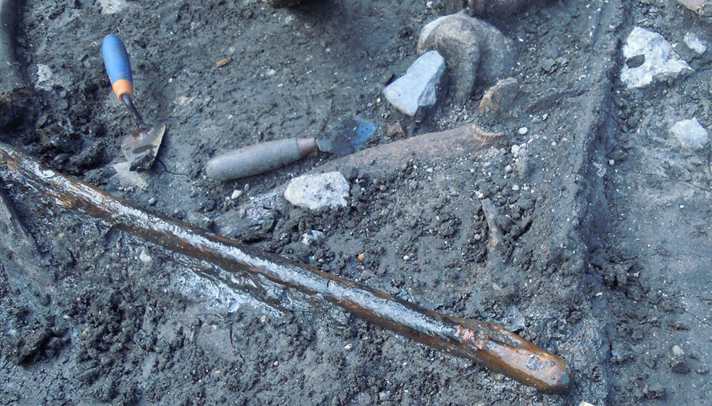 a photo of a digging site, showing a digging stick and where it was unearthed