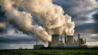 a photo of steam coming from giant cooling towers at a coal power plant
