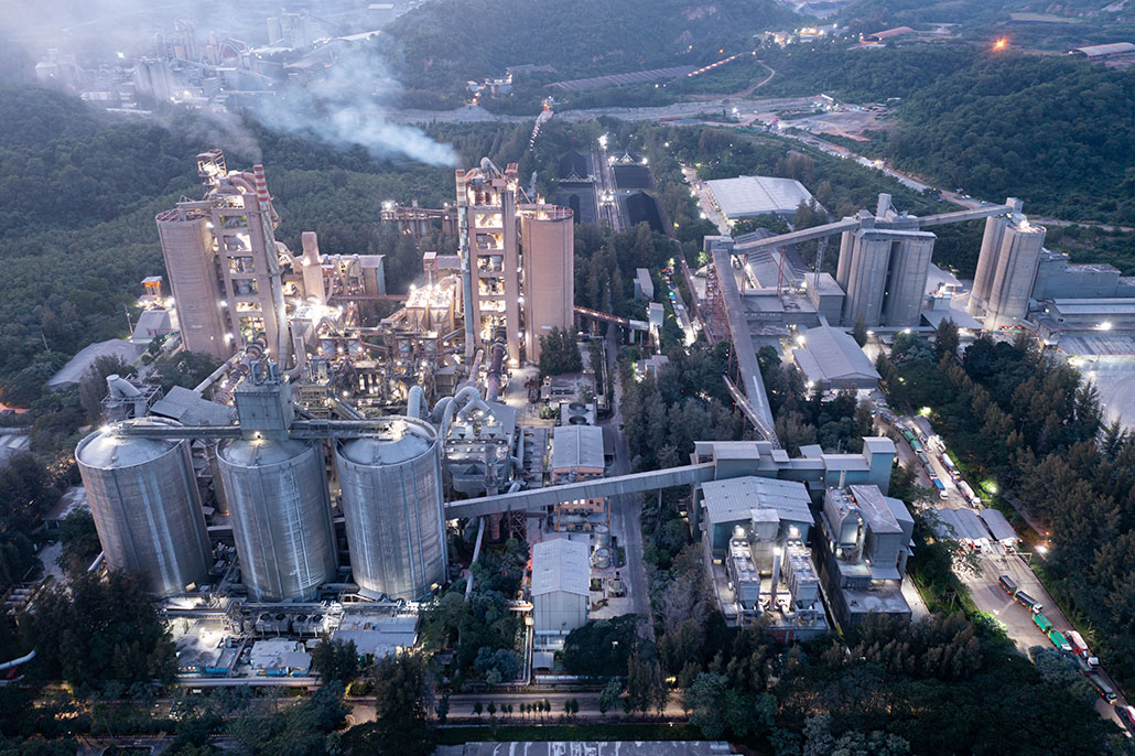 an aerial view of a cement factory with smoke actively being released from smokestacks