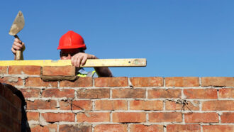 a photo of a brick layer checking to make sure the bricks are level
