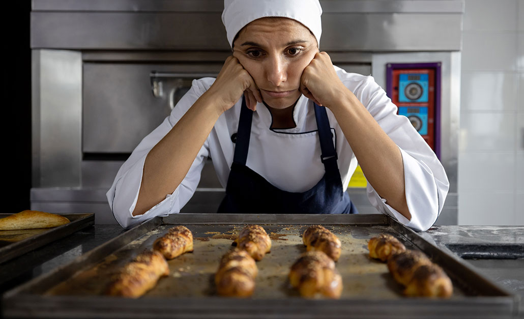 a photo of a sad baker looking at an unappetizing baking sheet of baked goods