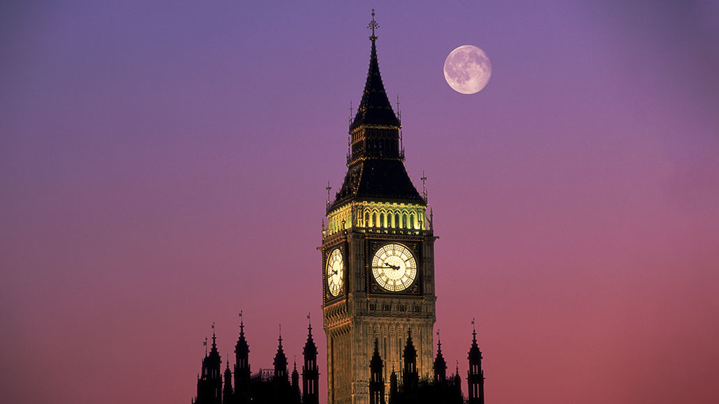 a photo of the Big Ben clock tower against a pink and purple sky. The moon can be seen near the pinnacle of the tower