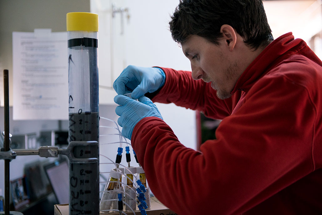 a photo of a male researcher in a lab, analyzing a sediment core