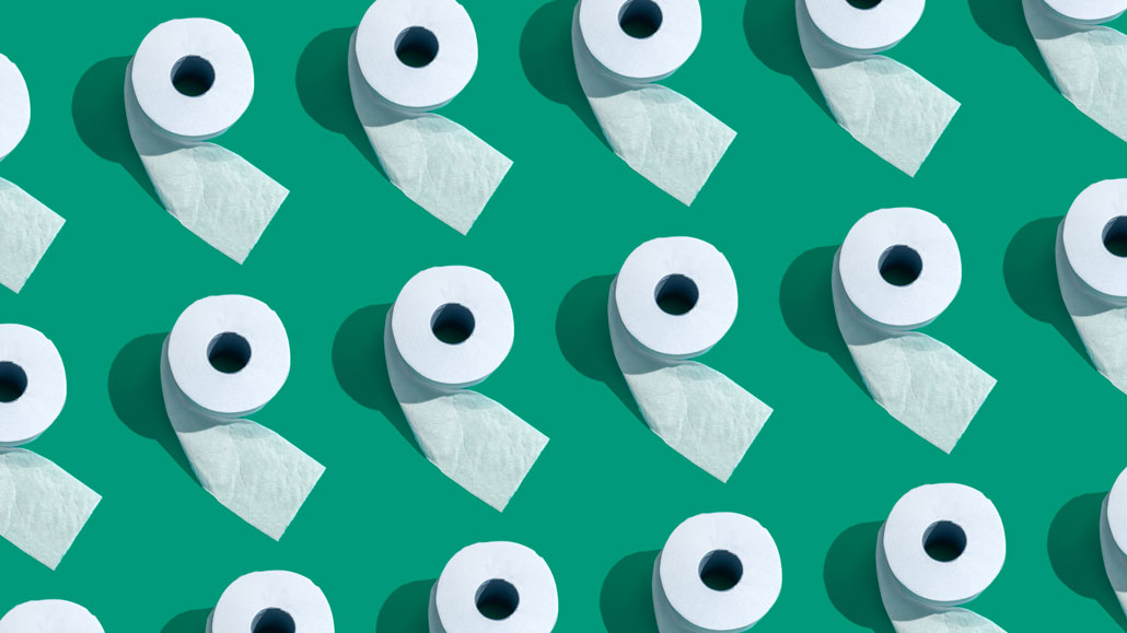 several rows of toilet paper as seen from above, against a green backdrop