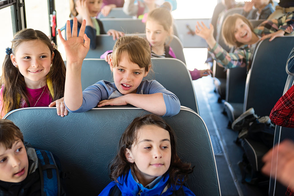 a candid photo of the inside of a schoolbus, there are at least two young students in every seat