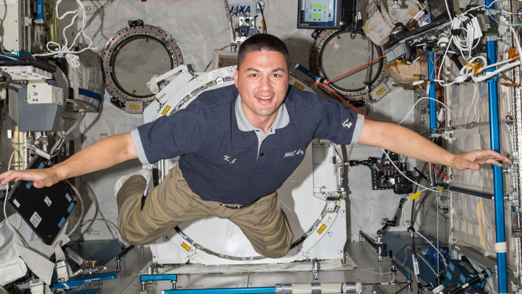 a photo of Kjell Lindrgren, a smiling white man with dark hair, floatin gin the space station