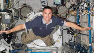a photo of Kjell Lindrgren, a smiling white man with dark hair, floatin gin the space station