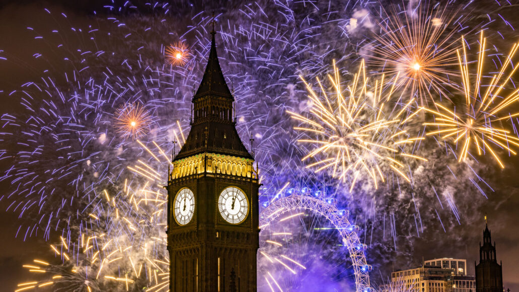 purple and gold fireworks explode in the night sky over big ben
