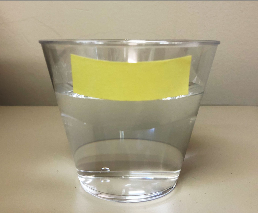 a photo of a glass of water, yellow masking tape on the outside markes the water level, which is about 1 inch below the rim of the glass
