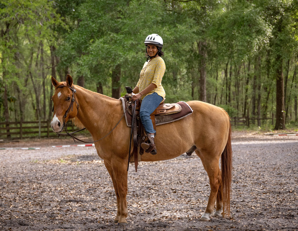 a photo of Eakta Jain astride a brown horse with a white nose and a white diamond in the middle of its forehead