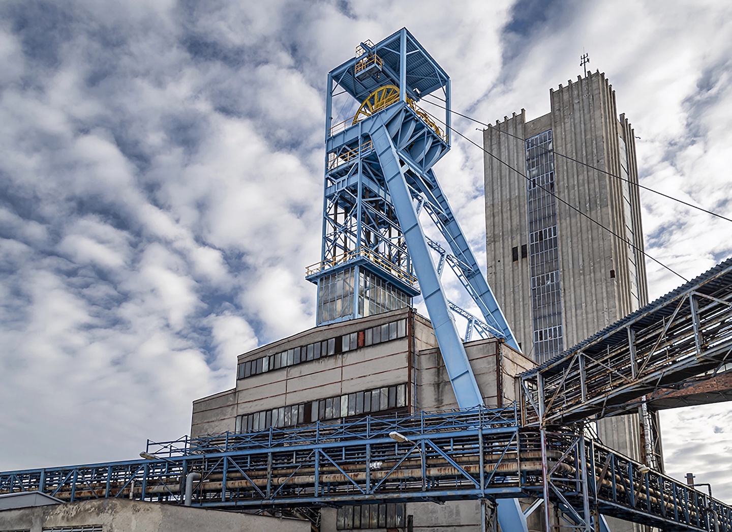 a complex, crane-like device extends above a building, equipped with pulleys and other machinery