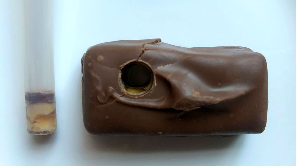 a fun-sized Snickers bar with a straw hole poked through it. The straw is to the left of the bar with the "core" inside it