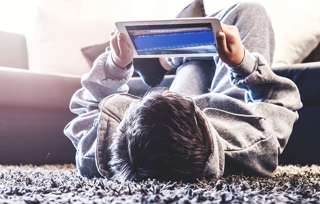 a young man lying on the floor holding a tablet above his head