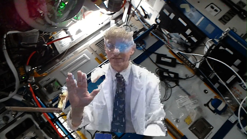 a photo of Josef Schmid holported onto the ISS, he has his hand raised in a Vulcan greeting