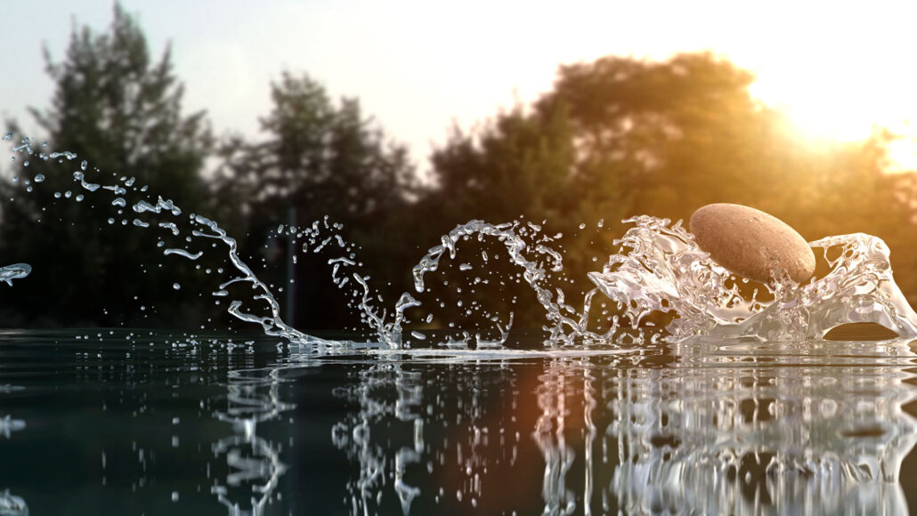 a stone kicks up three arcs of water behind it as it skips over the surface of a pond, with sun shining through trees in the background