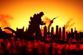 A silhouette of Godzilla stands over a ruined city. The background glows an ominous yellow and orange