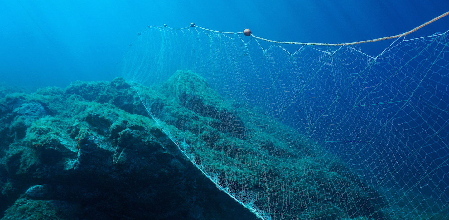 Fishing net under water gillnet in the ocean with rock and blue water
