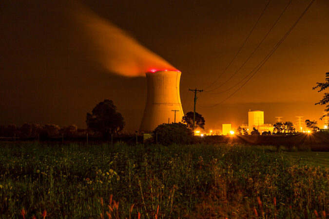 a photo of steam rising from a nuclear power plant cooling tower at night