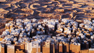 an aerial view of a city with many tall brown and white buildings surrounded by a desert