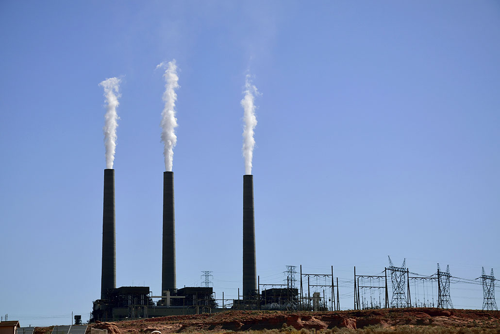 a photo of white exhaust rising from smokestacks at a powerplant