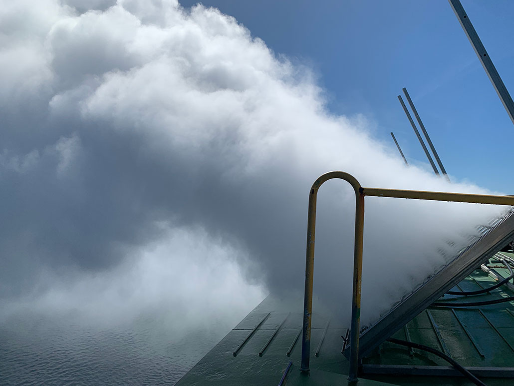 a photo of an apparatus creating a cloud of fog over water