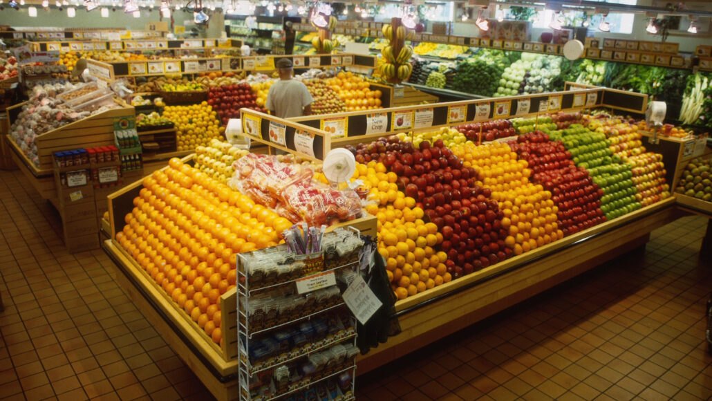 The produce section of a grocery store with lots of fruit and vegetables on sloped displays