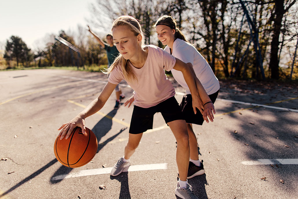 a girl bouncing a basketball on a basketball court