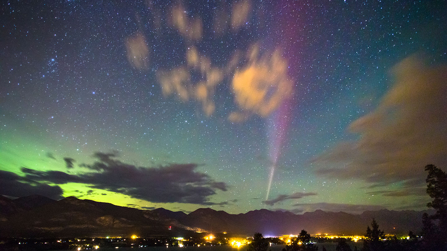 the mysterious skyglow known as STEVE is seen just off center in the night sky. On the far left bottom horizon is a green aurora.
