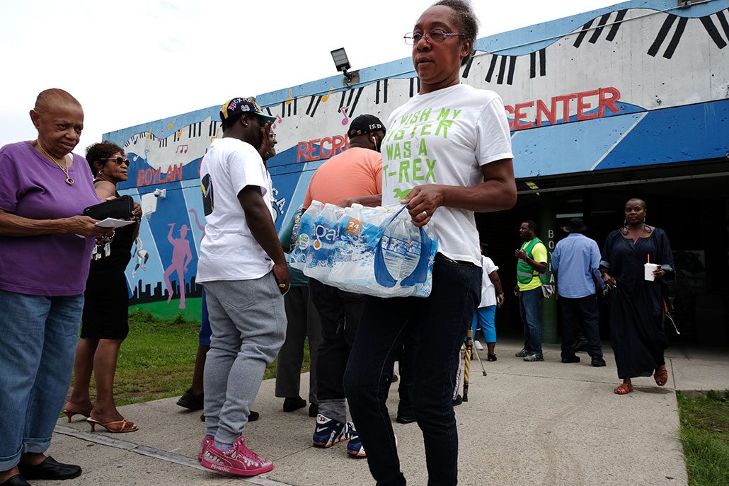 a woman carries bottled water away from a distribution center