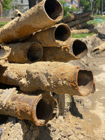 a photo of lead water pipes removed from the ground and stacked on top of each other