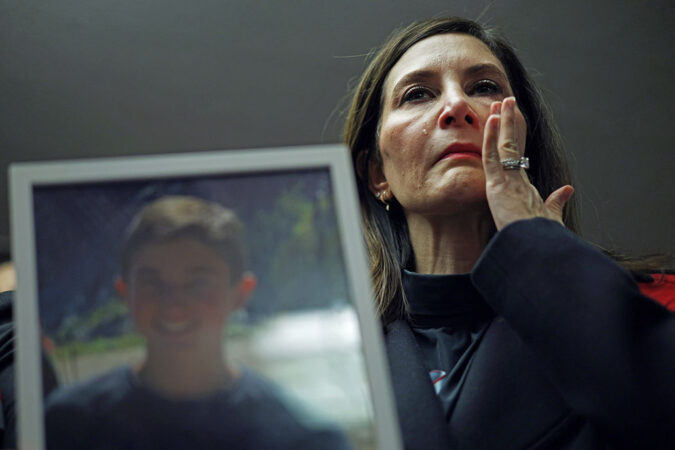 A middle-aged woman is holding an out-of-focus image of her son and crying