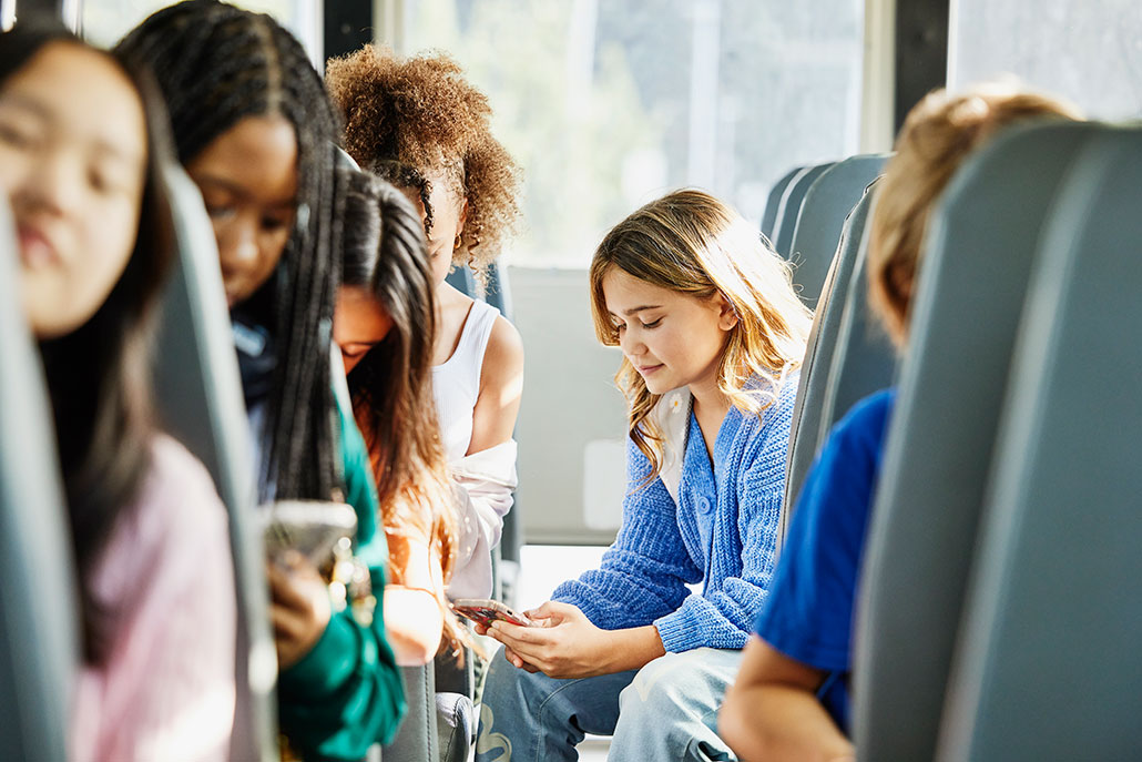 a photo of teens on a bus using social media