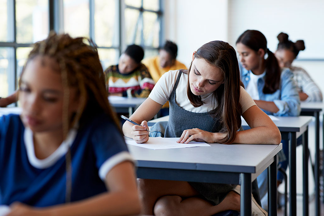 a photo of teenagers in a classroom taking exams