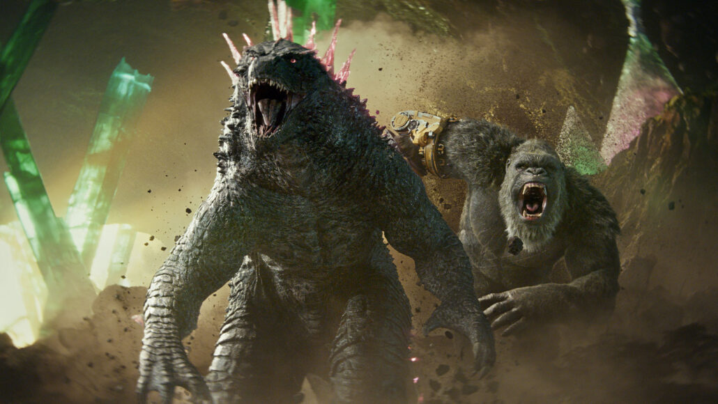 godzilla and king kong race through an underground cave, both of their jaws open to roar
