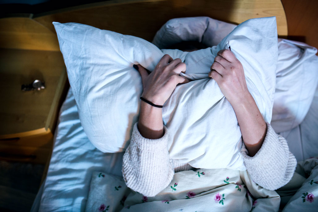 a person laying in bed covering their face with a pillow