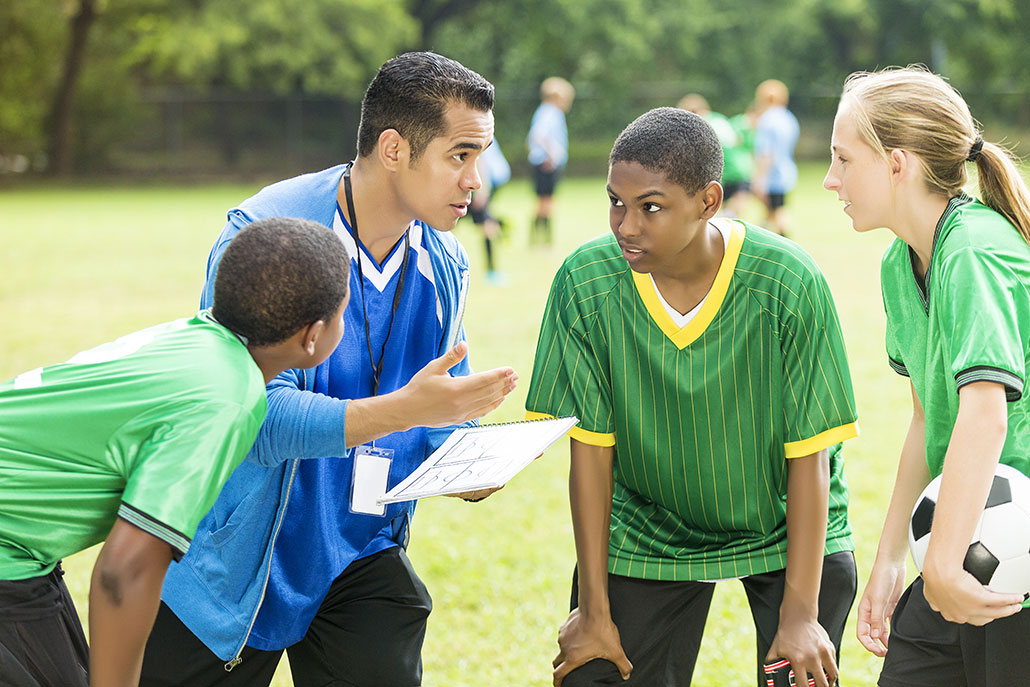 A group of young soccer players listening to their coach on the field 