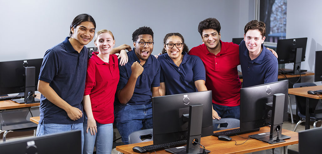 a group of teens in a computer lab wearing red shirts and blue shirts