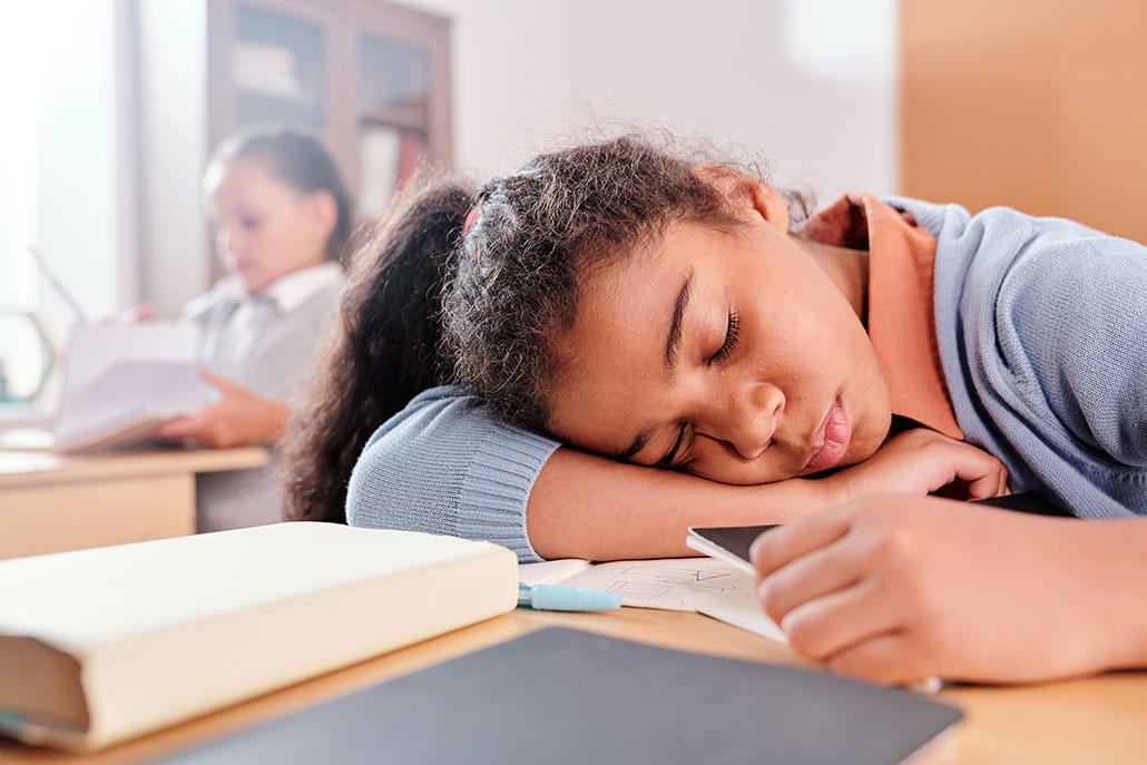a girl sleeping on her desk in a classroom