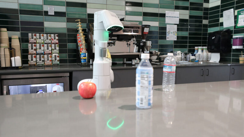 a robot looking at two bottles on a counter