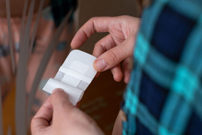 a view of hands holding and opening a white rectangular patch