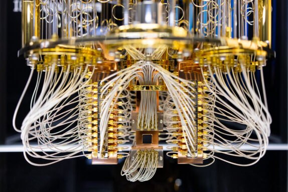 a circular structure with a shiny gold metal supports and silvery white wires runing throughout - it almost looks like a chandelier. At the very bottom there is a dark rectangle that all the wires seem to connect to, the quantum-processing chip.