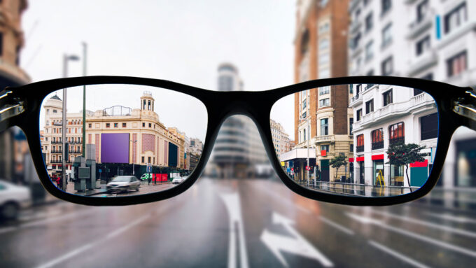 an illustration showing a photo of a city through glasses (in focus) and the city outside of the glasses (out of focus)