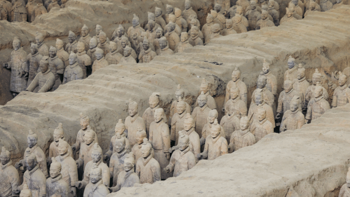 rows of terra cotta soldiers stand guard around a tomb
