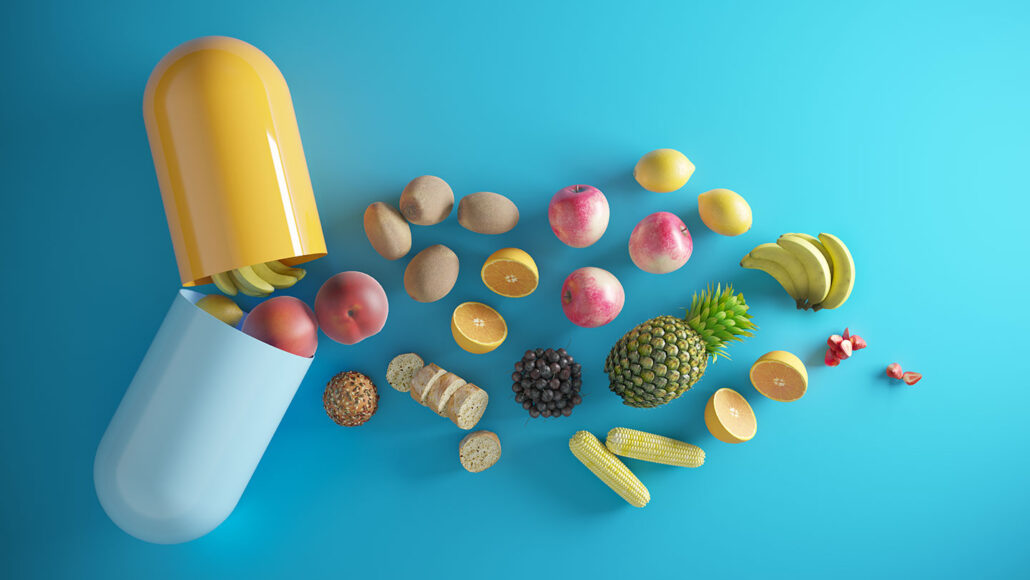 an illustration showing fruits, vegetables and other foods falling out of an open pill capsule meant to represent a vitamin supplement