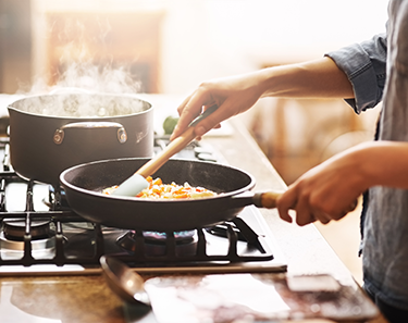 a photo of hands cooking with a frying pan on a stovetop
