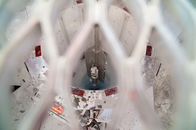 The sediment “corer” descends toward Lake Whillans, through a hole drilled in the ice. The hole is 800 meters (half a mile) deep and no wider than a pizza. The equipment is being viewed through the platform (blurred lattice-work in this image) on which workers can stand. Credit: © JT Thomas