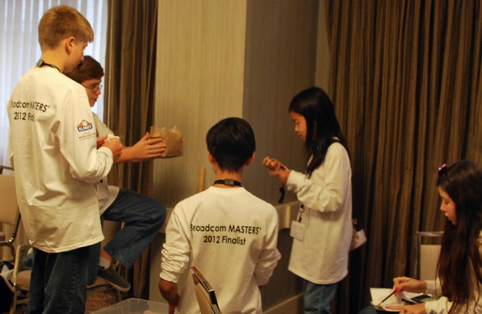 Students on the White Team — one of six at the 2012 Broadcom MASTERS competition — participate in the egg drop challenge. This group used packing peanuts and bubble wrap to try to protect a raw egg in a brown paper bag from cracking when dropped. Credit: