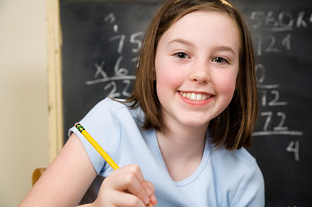 a girl holding a pencil and smiling in front of a chalkboard full of math problems
