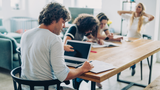 a photo of a family sitting a table teleworking and doing homework