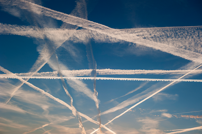 a photo of jet contrails criss-crossing a blue sky
